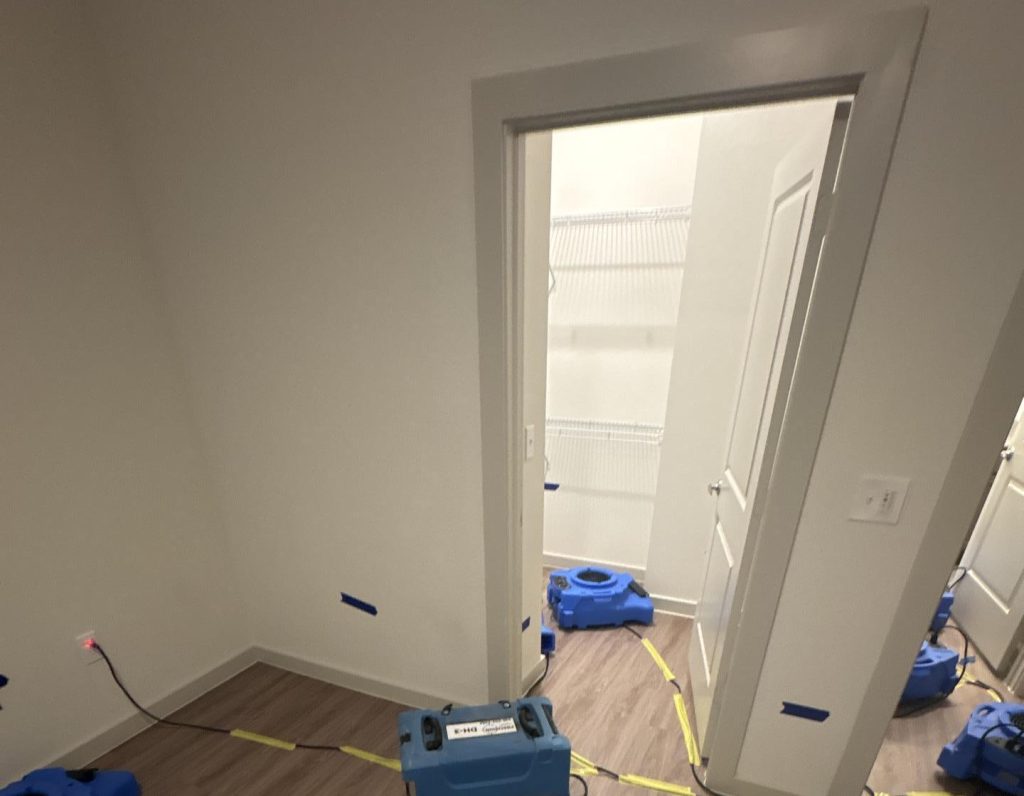 A recently remediated room with air movers, dehumidifiers, and containment tape set up to ensure proper drying and mold prevention. The image is part of a promotional card with a red background labeled 'RESTORATION AND CLEANUP.' The text explains the process of restoring damaged materials, cleaning affected areas with antimicrobial solutions, preventing future mold growth, and performing final clearance testing. This service is essential for mold treatment Houston and mold remediation companies Houston, ensuring a thorough and professional mold removal process.