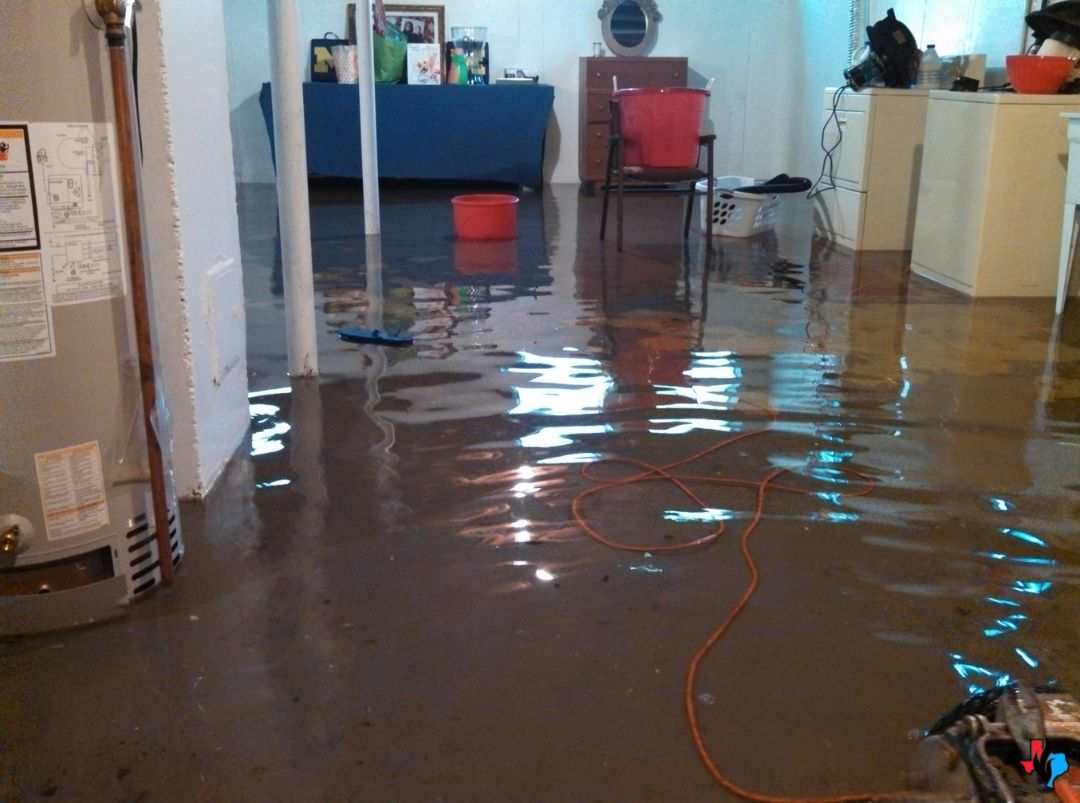 A flooded basement with standing water from a burst pipe in Spring, TX. This water damage restoration scene shows soaked flooring and household items needing immediate cleanup.