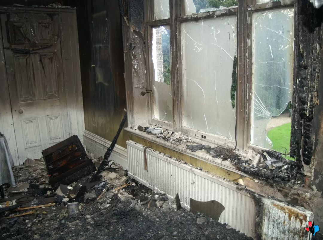 Fire Damage Restoration Experts in Magnolia, TX – Severely burned room with charred debris on the floor, blackened walls, and broken, soot-covered windows. Precision Restoration offers 24/7 fire damage restoration services in Magnolia, TX, helping property owners recover safely from fire, smoke, and soot damage.