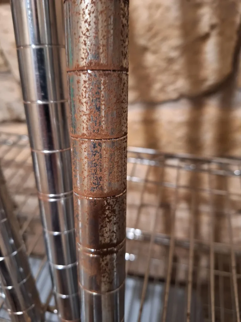 a metal shelving unit with visible rust and corrosion on one of the vertical support poles.