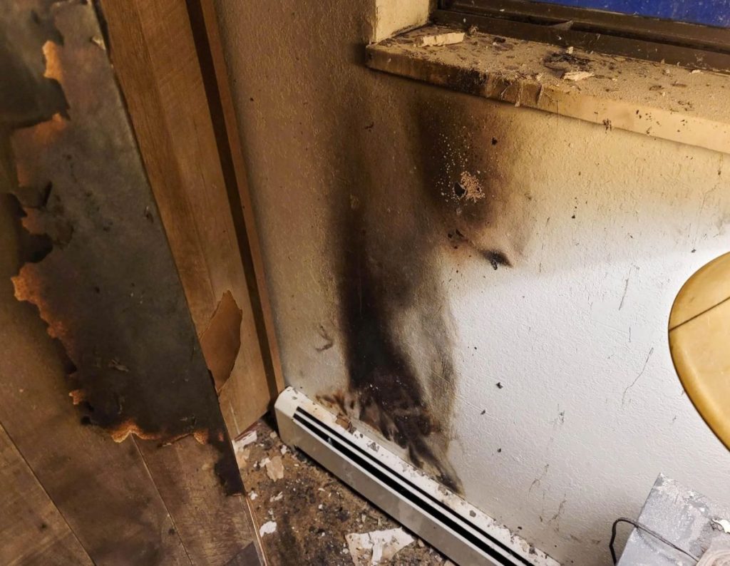 Smoke damage on an interior wall and baseboard after a fire, showing severe staining and soot buildup — related to smoke odor in Houston TX.